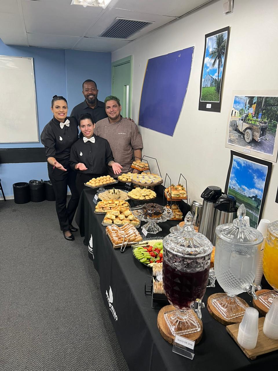 Mesa de buffet com lanches e pessoas ao lado